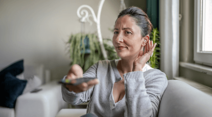 Woman turning up volume on her TV